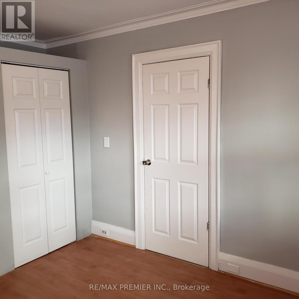 A room with two doors and a brokerage sign.
