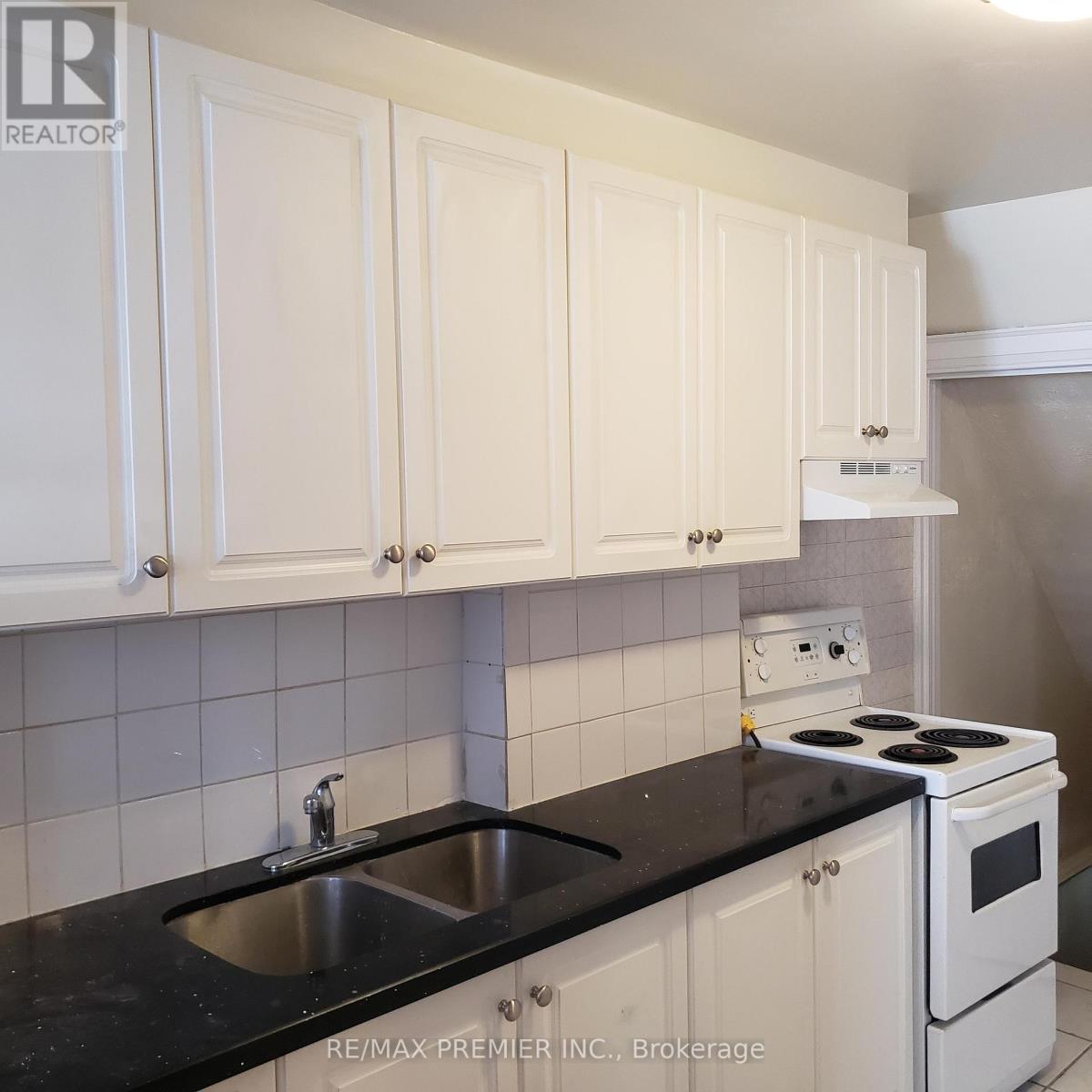 A kitchen with white cabinets and black countertops.