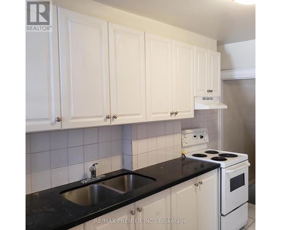 A kitchen with white cabinets and black countertops.