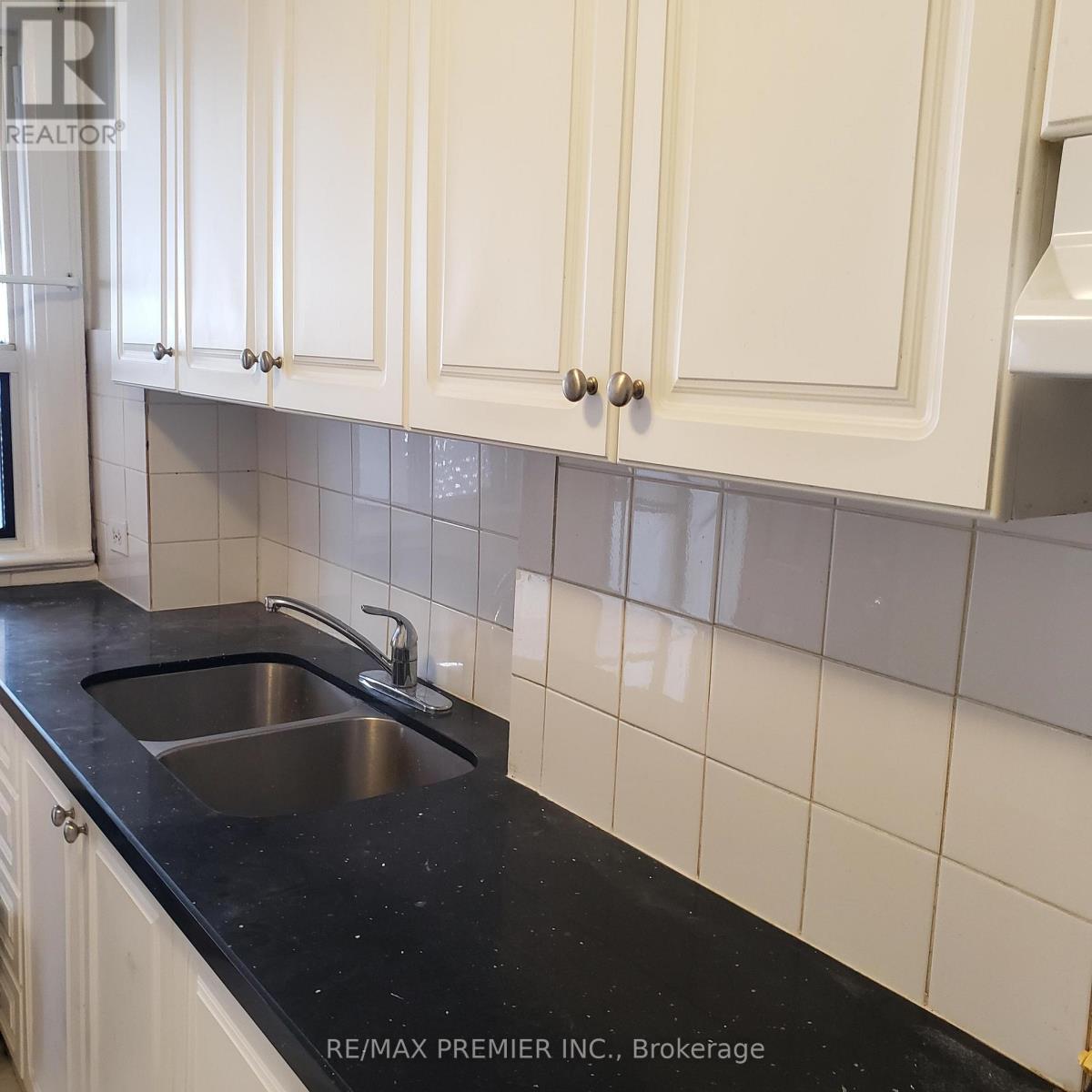 A kitchen with white cabinets and a black counter top.