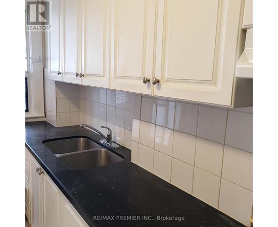 A kitchen with white cabinets and a black counter top.