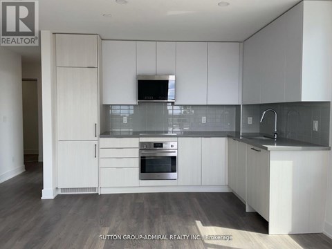 A modern kitchen with white cabinets and a wooden floor.