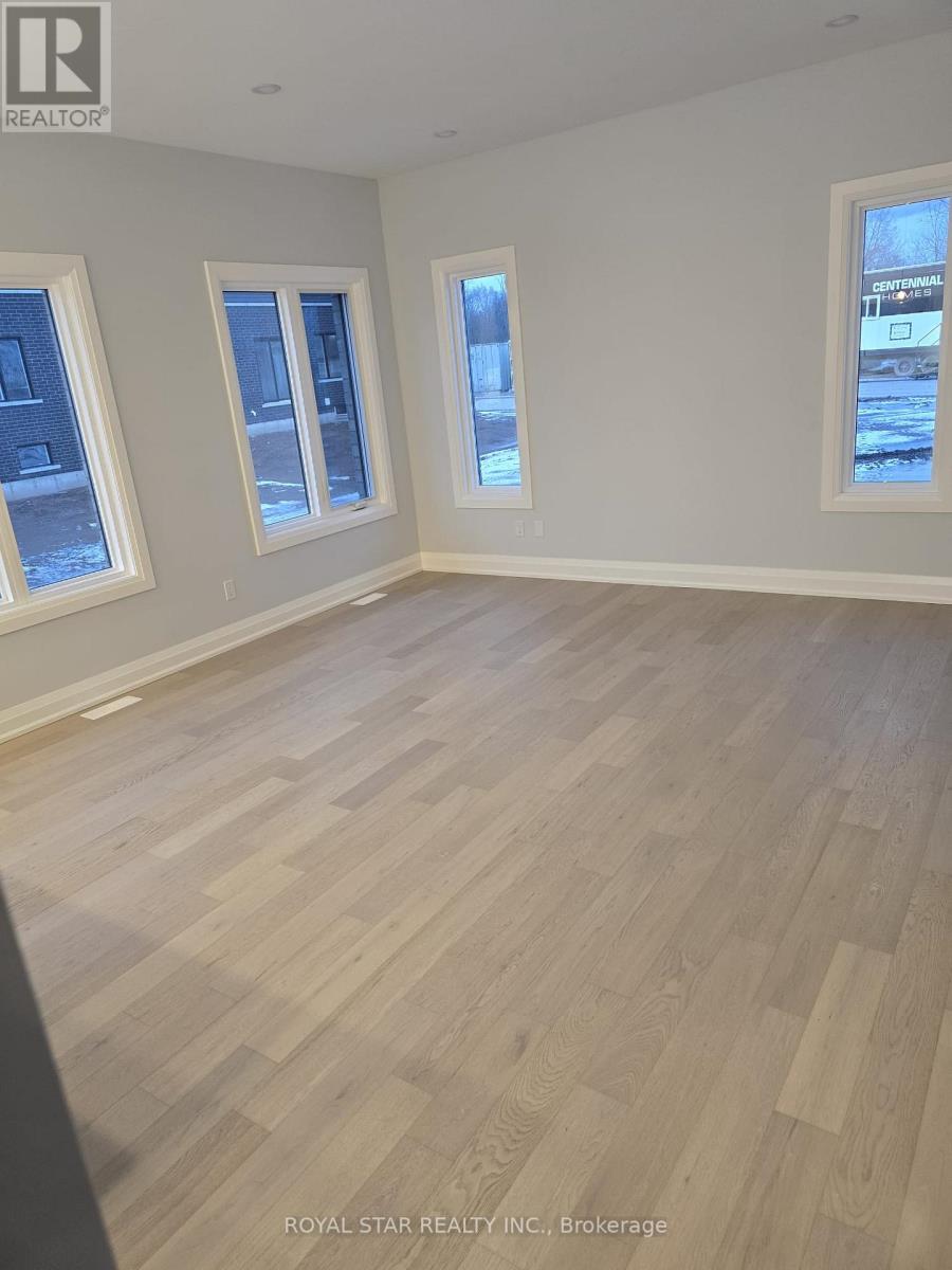 A room with wooden flooring and three windows.