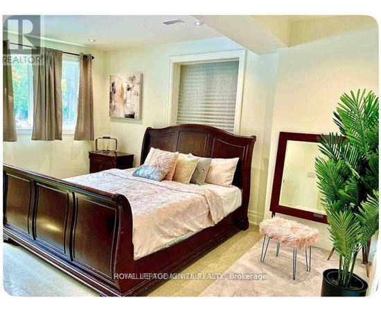 A bedroom with a large bed and a potted plant.