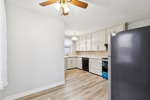 A kitchen with a black refrigerator and wooden floors.