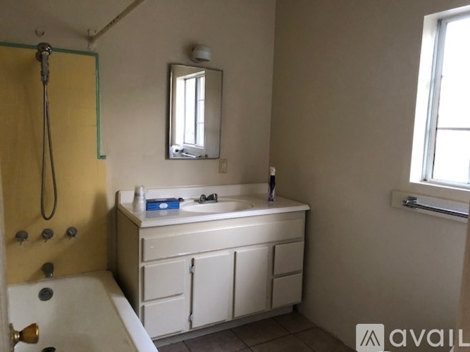 A bathroom with a white tub and sink, a mirror, and a window.