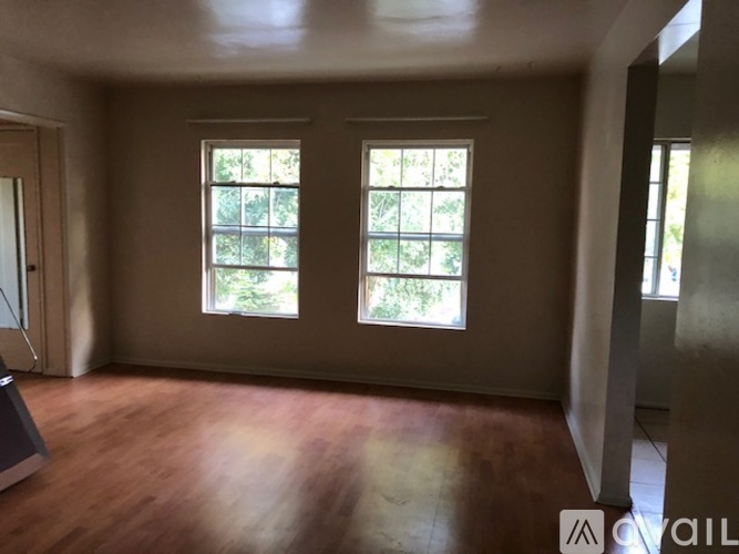 A room with wooden floors and two windows.