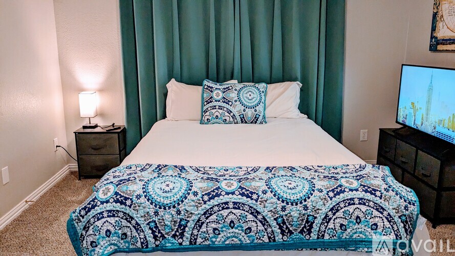 A bed with a blue and white patterned comforter is in the image.