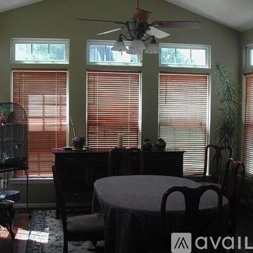 A room with a table, chairs, and a ceiling fan.