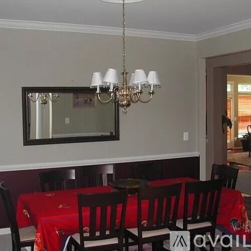 A dining room with a red tablecloth and wooden chairs.