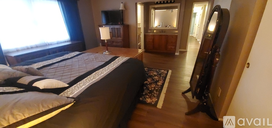 A bedroom with a large bed and a dresser with a mirror.