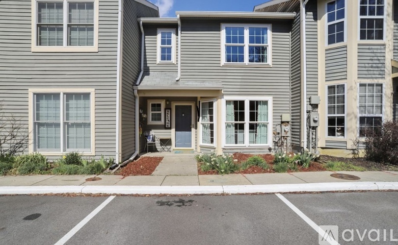 A grey two-story apartment building with a front yard and a driveway.