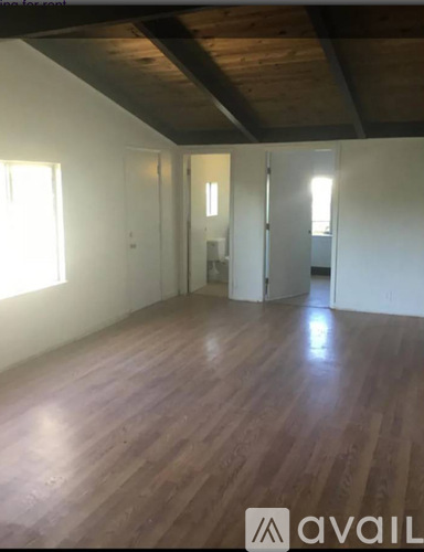 A room with wooden floors and a window on the left side.