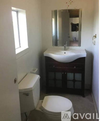 A bathroom with a toilet, sink, and mirror.