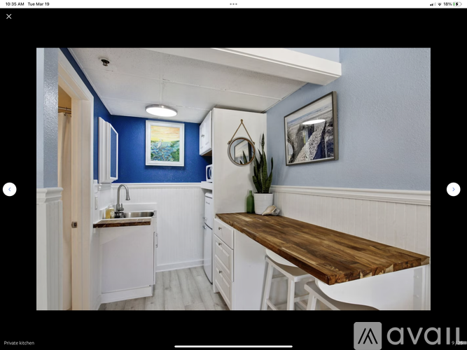 A kitchen with blue walls and white cabinets.