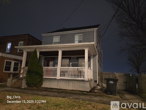 A house with a porch and a tree in front of it.