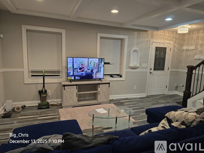 A living room with a television on a stand and a vacuum cleaner on the floor.