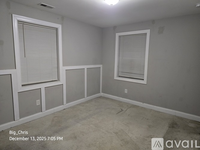 A room with two windows and a wall-mounted air conditioning unit.