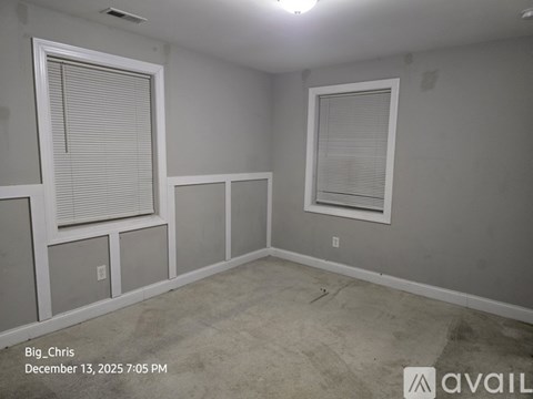 A room with two windows and a wall-mounted air conditioning unit.