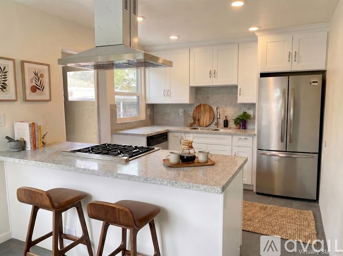 A modern kitchen with a marble countertop and stainless steel appliances.