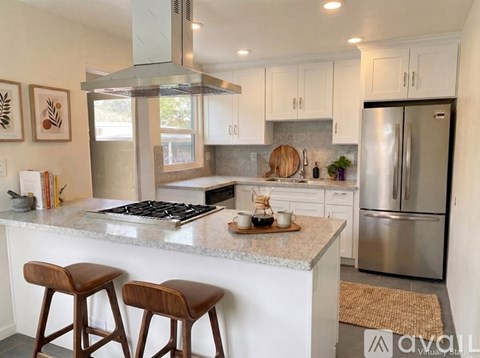 A modern kitchen with a marble countertop and stainless steel appliances.