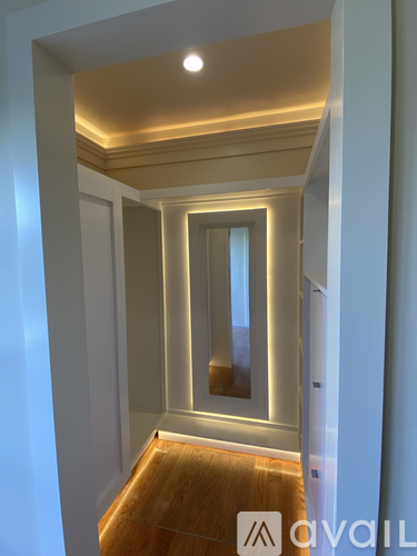 A hallway with a wooden floor and white walls.