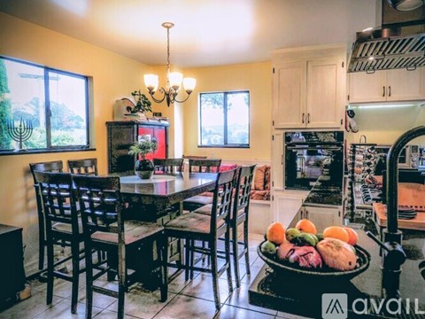 A kitchen with a table and chairs and a bowl of fruit on the counter.