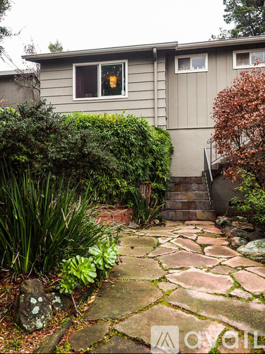 A grey house with a stone pathway leading to the front door.