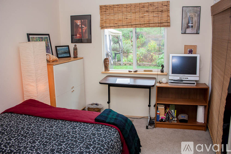 A bedroom with a bed, desk, and window.