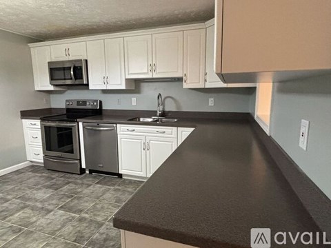 A kitchen with white cabinets and a black countertop.