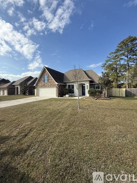 A house with a brown roof and a white garage door is surrounded by a grassy lawn.