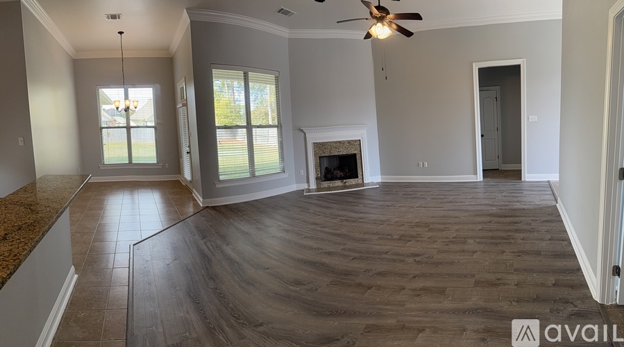 A spacious living room with a fireplace and a ceiling fan.