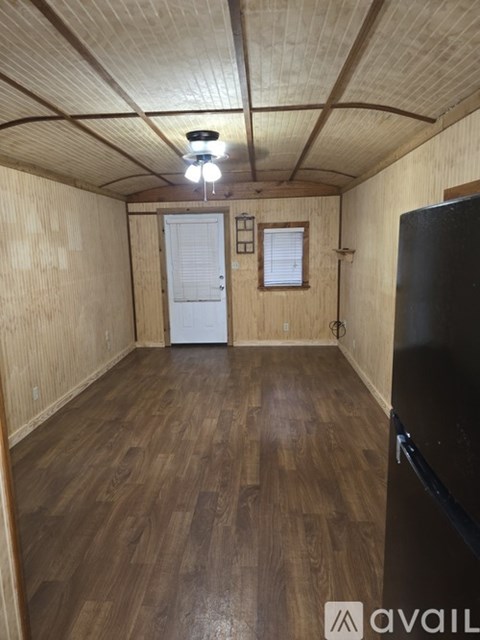 A room with wooden floors and a black refrigerator.