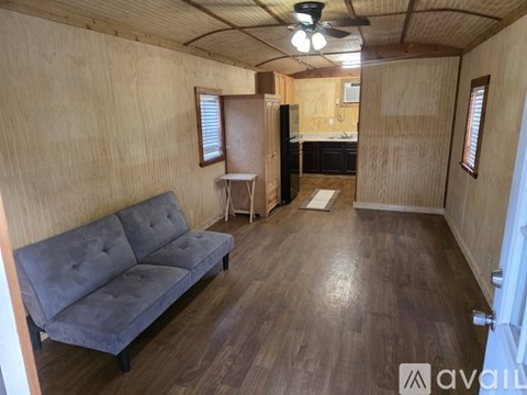 A room with wooden walls and a black refrigerator.