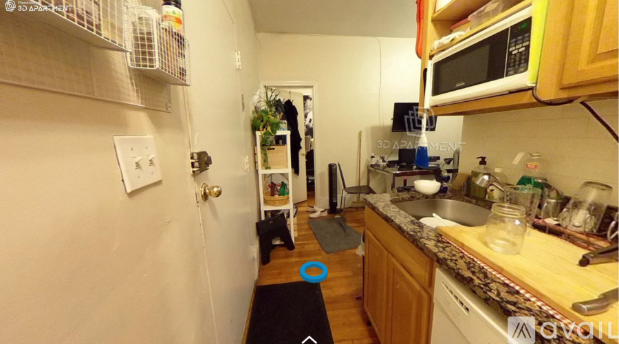A kitchen with a sink, microwave, and a door leading to a hallway.