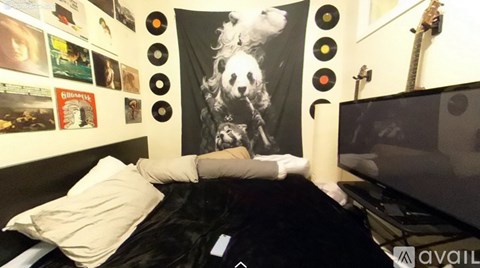 A person is lying on a bed with a poster of a woman's face on the wall behind them.