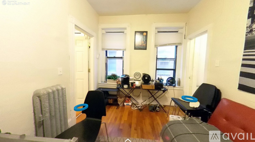 A living room with a black couch, a coffee table, and a red chair.
