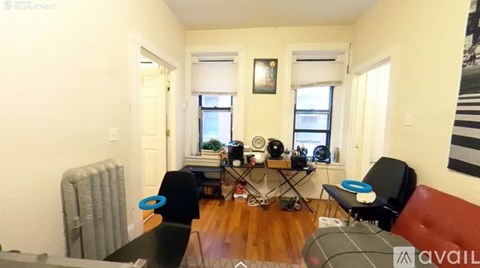 A living room with a black couch, a coffee table, and a red chair.