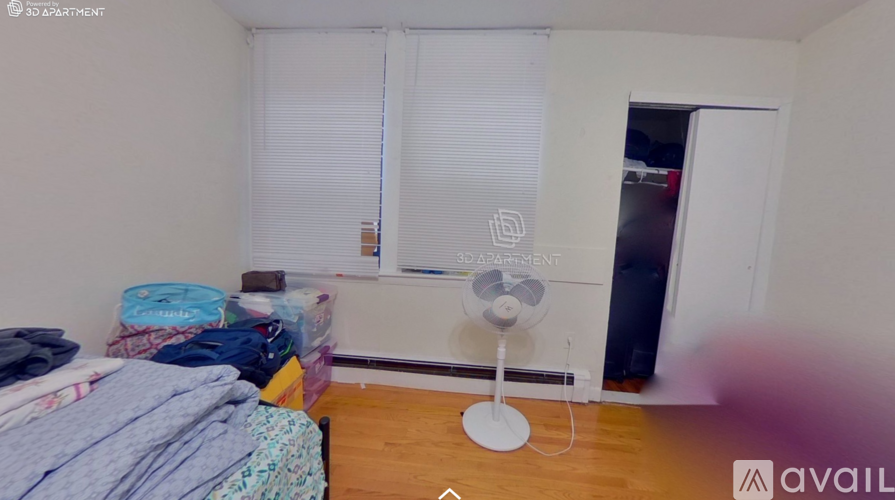 A bedroom with a bed, a fan, and a window with blinds.