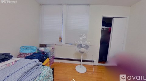 A bedroom with a bed, a fan, and a window with blinds.