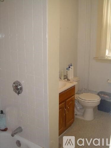 A bathroom with a white toilet and a white tiled shower.
