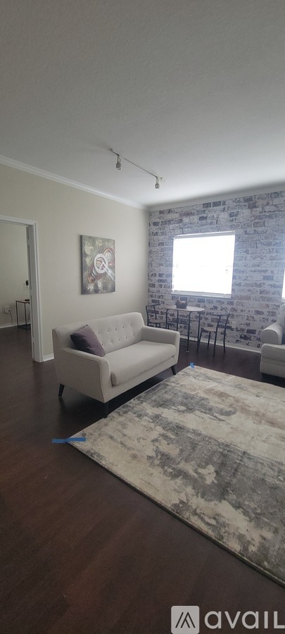A living room with a couch, a rug, and a painting on the wall.