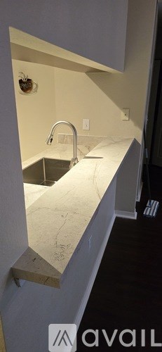 A kitchen counter with a sink and a wall-mounted light fixture.