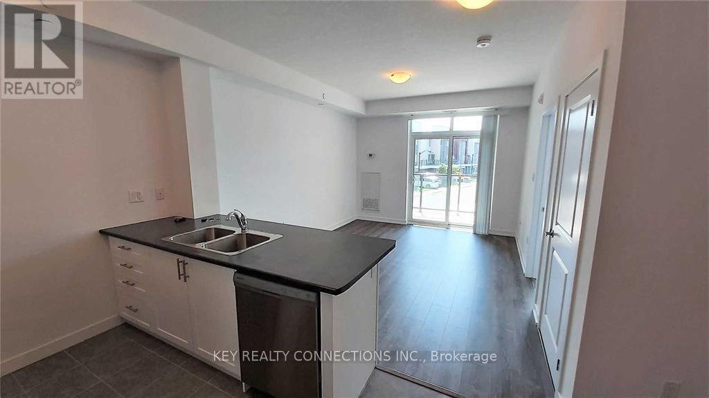 A kitchen with a sink and a dishwasher in a room with a door leading to another room.