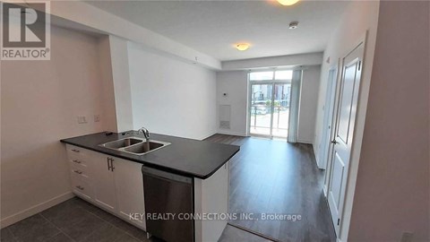 A kitchen with a sink and a dishwasher in a room with a door leading to another room.