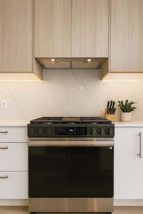 A black stove top oven sits under a cabinet in a modern kitchen.