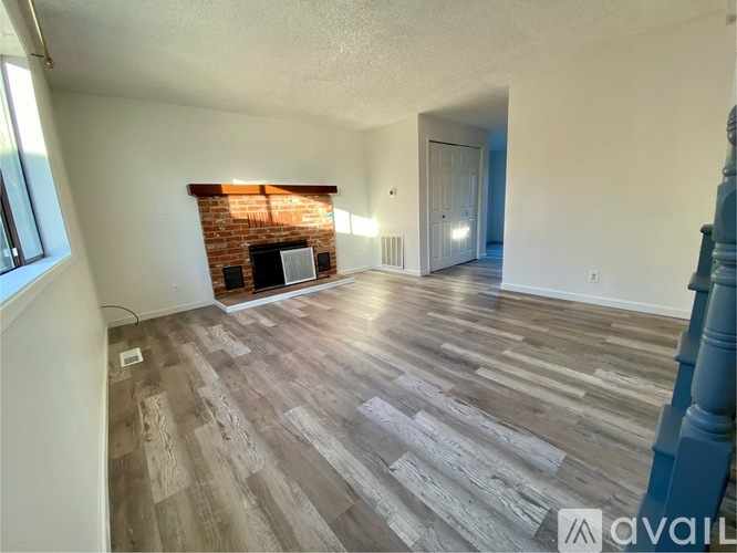 A room with a brick fireplace and wooden flooring.