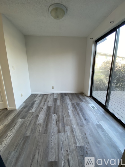 A room with wooden flooring and a sliding glass door.