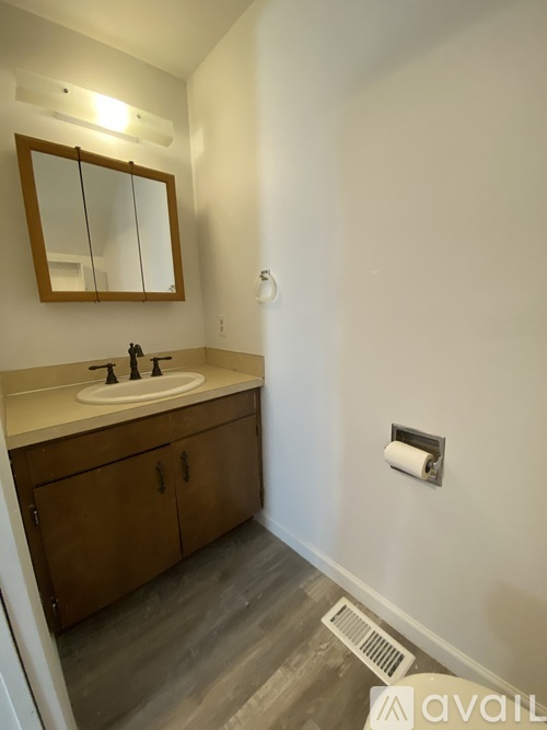 A bathroom with a sink, mirror, and wooden cabinets.