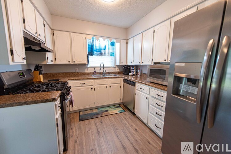 A kitchen with white cabinets and a stainless steel refrigerator.